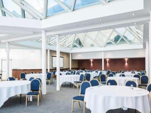 a room with white tables and chairs and windows at Mercure St Helens in Saint Helens