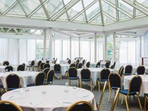 Cette chambre dispose de tables et de chaises blanches ainsi que de fenêtres. dans l'établissement Mercure St Helens, à St Helens