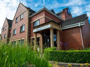 a red brick building with columns and plants at Ibis Budget Bromsgrove in Bromsgrove