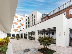 un grand bâtiment blanc avec des fenêtres et une cour dans l'établissement Novotel Münster City, à Münster