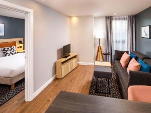 um quarto de hotel com uma cama e um sofá em Aparthotel Adagio London Sutton Point em Sutton