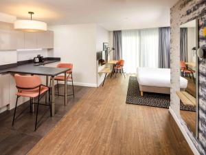 a kitchen and living room with a table and chairs at Aparthotel Adagio London Sutton Point in Sutton