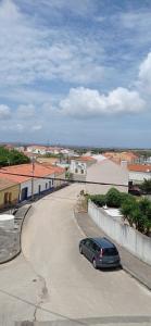 a car parked in a parking lot next to a street at Alojamento Dona Inês de Castro in Atouguia da Baleia