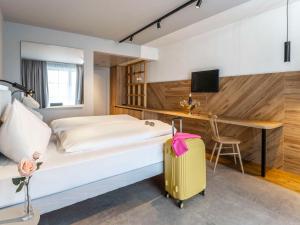 una camera d'albergo con un letto e una valigia gialla di ibis Styles Graz Messe a Graz