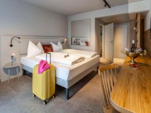 - une chambre avec un grand lit et une valise jaune dans l'établissement ibis Styles Graz Messe, à Graz