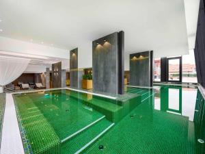 basen z zieloną podłogą w budynku w obiekcie Mercure Tokaj Center w Tokaju