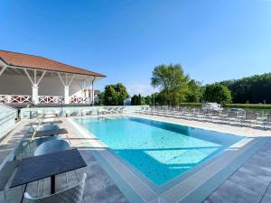 a large swimming pool with chairs and a building at Mercure Tokaj Center in Tokaj
