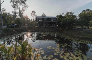 une maison avec un étang en face de celle-ci dans l'établissement เป่าฟู่เฮ้าส์ Bao Fu's House, à Chumpon