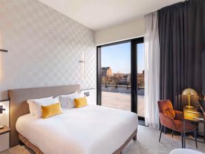 Una habitación de hotel con una cama y una ventana grande. en Mercure Namur Hotel, en Namur