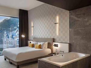 a hotel room with a bed and a bath tub at Mercure Namur Hotel in Namur