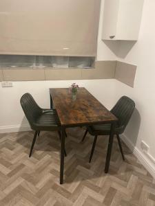 een houten tafel met twee stoelen en een vaas met bloemen erop bij Edgware Rooms in Stone Grove