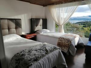 2 camas en una habitación con ventana grande en Chalet_Laguna_Azul, en Aquitania