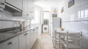 a white kitchen with a table and a white refrigerator at Ático Laxe Grande in A Guarda