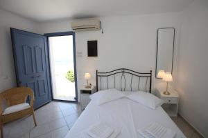 Un dormitorio con una gran cama blanca y una ventana en Captain's Nest, en Ándros