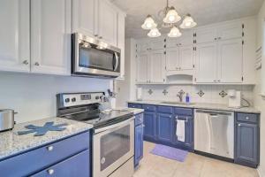 una cocina con armarios blancos y electrodomésticos azules en Pool home sleeps 6 with large fenced yard en Jacksonville