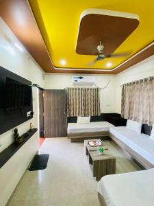 een woonkamer met 2 bedden en een geel plafond bij PATEL HOME STAY in Garudeshwar