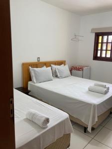 2 camas en un dormitorio con sábanas blancas y toallas en Ipê Suites Juquehy, en Juquei