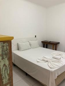 1 dormitorio con 1 cama con sábanas blancas y mesa en Ipê Suites Juquehy, en Juquei