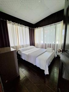 1 dormitorio con 1 cama con sábanas blancas y ventanas en Hospedaje Finca Agroturistica Doña Rufa, en Río Sereno