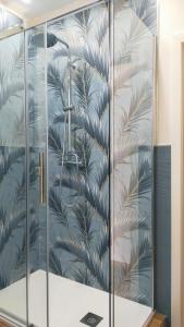 une douche en verre avec une fresque murale représentant des feuilles de palmier dans l'établissement A.Mare, à Stintino