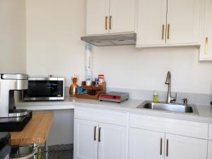 a kitchen with white cabinets and a sink and a microwave at Calafia Inn San Clemente Newly renovated in San Clemente