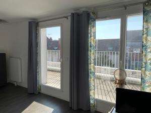 um quarto com 2 janelas com cortinas e uma varanda em Place verte 2302 em Lille