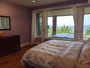 a bedroom with a bed and a large window at Mountain House of Wonder in Qualicum Beach
