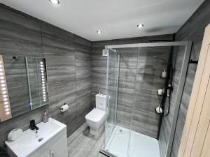 uma casa de banho com um chuveiro, um WC e um lavatório. em Entire Two Bedroom Guest Home Free Parking em Nottingham