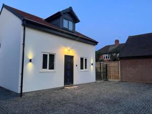 a white house with a black door and a fence at Entire Two Bedroom Guest House & Free Parking in Nottingham