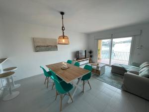 a living room with a wooden table and green chairs at Aquamarine Sant Feliu en la playa con patio in Sant Feliu de Guixols