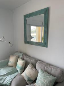 a mirror hanging above a couch with pillows at Aquamarine Sant Feliu en la playa con patio in Sant Feliu de Guixols