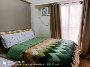 ein Schlafzimmer mit einem Bett mit einer Bettdecke und einem Fenster in der Unterkunft Spacious 1 BR condo unit Near NAIA in Manila