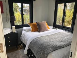 a bedroom with a bed and two windows at Adorable little container house in Hastings