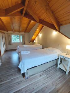 1 dormitorio con 2 camas y techo de madera en Cabaña Los Amancays en Villa La Angostura