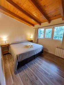 um quarto com uma cama grande num quarto com janelas em Cabaña Los Amancays em Villa La Angostura