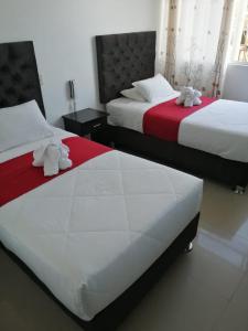 2 posti letto in camera d'albergo con lenzuola bianche e rosse di HOTEL LUCERO PARACAS a Paracas