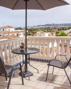 una mesa y sillas en un balcón con sombrilla en Casa Valentina en Jávea