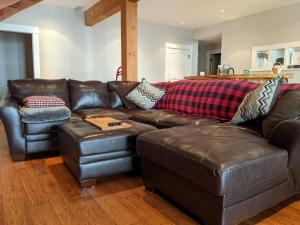 a living room with a brown leather couch at Mountain House of Wonder in Qualicum Beach