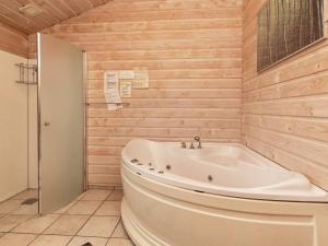 baño con bañera blanca y paredes de madera en 10 person holiday home in Thisted, en Klitmøller