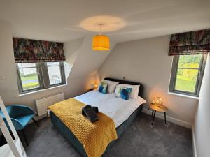 ein kleines Schlafzimmer mit einem Bett und zwei Fenstern in der Unterkunft Chic Classy & Cosy in Lough Erne 5* Resort in Ballycassidy