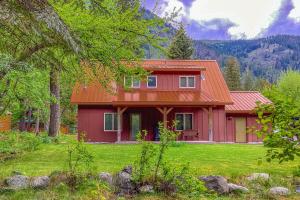 a red house with an orange roof in a yard at Wallowa Lake Wonder in Joseph