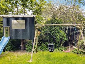 un parque infantil con un columpio en un patio en 8 person holiday home in Gr sted en Udsholt Sand