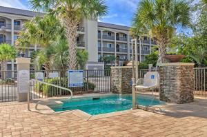 a swimming pool in front of a building with palm trees at Miramar Beach Condo with Pool - Walk to Beach! in Destin
