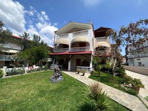 a large white house with a lawn in front of it at THE FLOWER APARTMENTS in Toroni