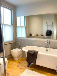 ein Badezimmer mit einer Badewanne, einem WC und einem Waschbecken in der Unterkunft Home in Chiswick Homefields in London