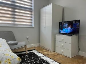 a living room with a tv and a white cabinet at Grand Bleu - London - Next to Piccadilly Line Tube Station & Brand New Facilities in London