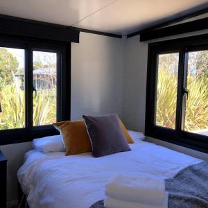 a bed in a room with two windows at Adorable little container house in Hastings