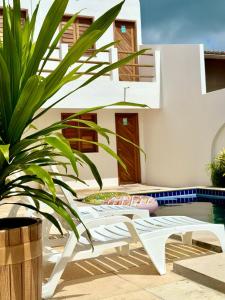 卡斯卡韋爾的住宿－Pousada Maré Forte，一个带白色椅子的庭院,毗邻游泳池