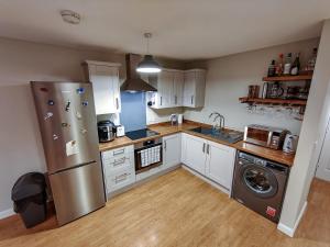 cocina con nevera de acero inoxidable y lavavajillas en Joshua Court Single Room en Stoke on Trent