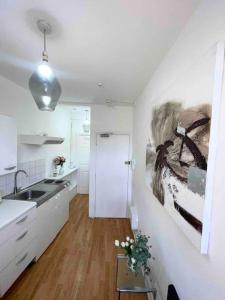 una cocina con fregadero y una pintura en la pared en Private Studio Flat close to Central London with Smart TV and workspace en Londres